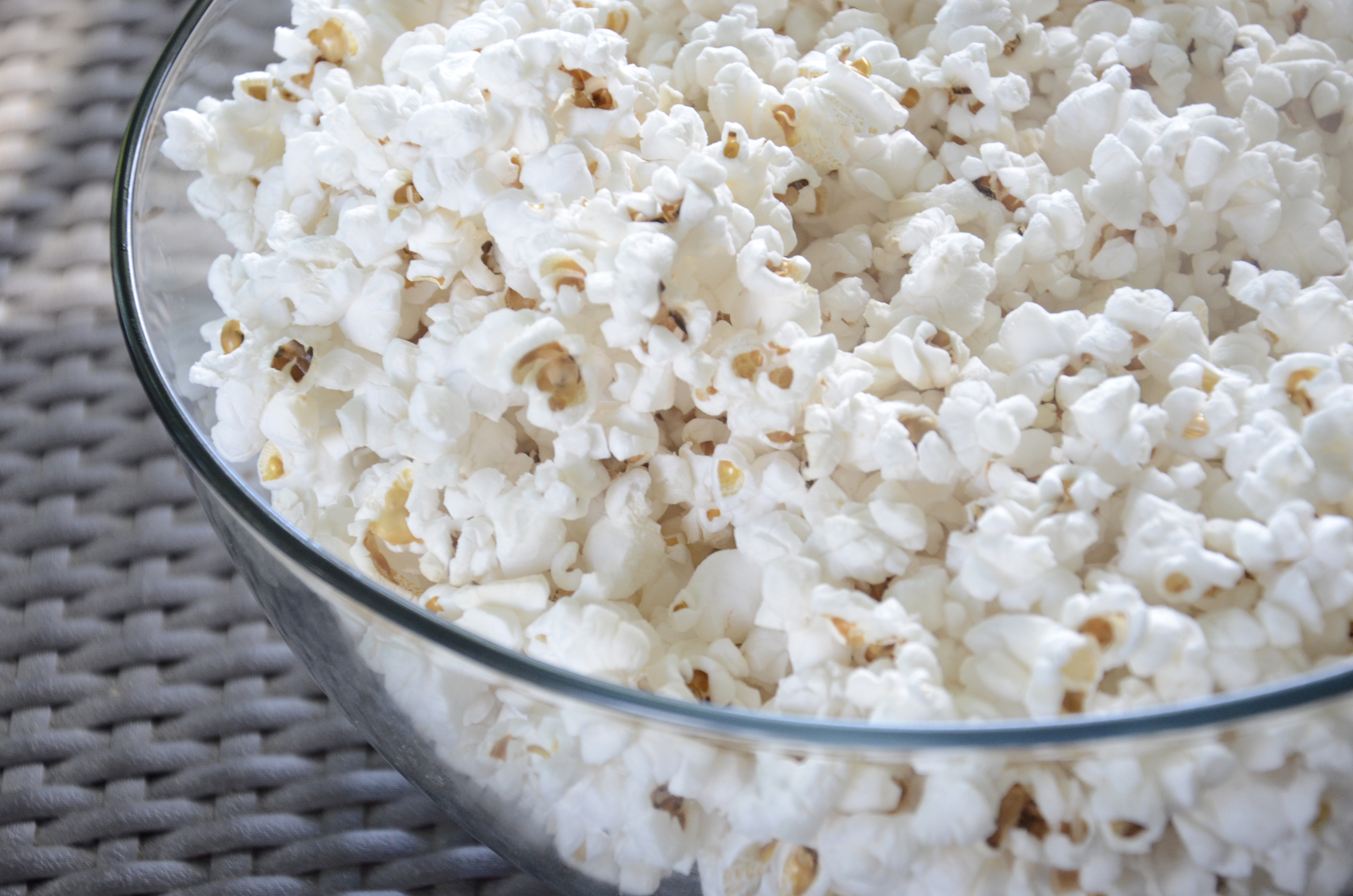 A glass bowl filled with freshly popped popcorn
